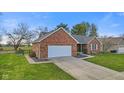 Exterior view of a red brick home featuring an attached two-car garage and green front lawn at 2511 Countryside Westview Dr, Shelbyville, IN 46176
