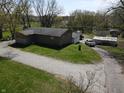 Aerial view of a home with well-kept lawn, gravel driveway, and outbuildings, surrounded by mature trees at 3311 Stella St, Greenwood, IN 46143