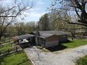 Home with a covered porch, stone chimney and a gravel driveway nestled in a serene, wooded setting at 3311 Stella St, Greenwood, IN 46143