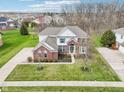 Expansive aerial view of a brick home with lush landscaping, long drive, and mature trees in a serene neighborhood at 3932 Long Ridge Blvd, Carmel, IN 46074