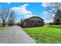 Ranch home with a brick facade and a long driveway leading to the property, surrounded by green lawn at 3991 Clubhouse Dr, Greenfield, IN 46140