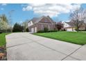 Long driveway leading to a brick home with a three-car garage, basketball hoop, and well-manicured lawn at 4281 Honeysuckle Ln, Zionsville, IN 46077