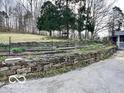 Stone retaining wall creates terraced levels on property, with mature trees and lush greenery at 5846 Bellsville Pike, Columbus, IN 47201
