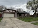Charming single-story home featuring stone accents, a two-car garage, and a well-maintained front yard at 613 Rahkewood Dr, Indianapolis, IN 46217