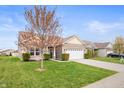 Beautifully landscaped front yard and charming brick home with two-car garage on a sunny day at 6323 Emerald Field Way, Indianapolis, IN 46221