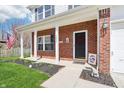 Inviting front porch with brick columns, a decorative wreath and a welcome sign at 7354 Ponderosa Pines Ln, Indianapolis, IN 46239