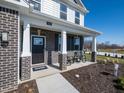 Inviting front porch with rocking chairs, brick columns, and a modern black front door at 7628 Big Bend Blvd, Camby, IN 46113