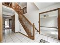 Entryway with tile flooring, wooden staircase, and doorway leading to a living area with a ceiling fan at 7688 Gunsmith Ct, Plainfield, IN 46168