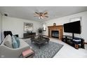 Cozy living room with a brick fireplace, ceiling fan, neutral furniture, and a large television at 7688 Gunsmith Ct, Plainfield, IN 46168