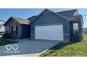 Blue home featuring a spacious driveway, two-car garage and attractive brick accents at 8019 Gathering Ln, Indianapolis, IN 46259