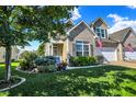 Well-manicured lawn and garden landscaping surround this inviting home, complemented by sunny skies and mature trees at 10955 Chapel Woods N Blvd, Noblesville, IN 46060