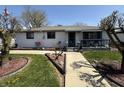 Quaint, white-brick home featuring manicured lawn, mature trees, and a covered porch entry at 1623 S Grant Ave, Indianapolis, IN 46203
