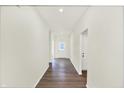 Bright hallway with hardwood floors and white walls leading to a glass-paneled door at 19113 River Jordan Pass, Westfield, IN 46074