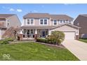 Charming two-story home boasts a manicured lawn, covered porch and attached two-car garage at 19546 Forsythe Dr, Noblesville, IN 46060