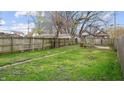 Spacious backyard featuring grass, purple flowers, and a tall wooden fence for privacy at 430 S Addison St, Indianapolis, IN 46222
