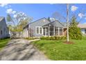 Charming gray home with well-manicured front lawn and driveway leading to the backyard at 6164 Evanston Ave, Indianapolis, IN 46220