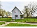 Charming two-story home featuring a fenced yard, covered porch, and traditional architecture with red shutters at 831 N 12Th St, Elwood, IN 46036