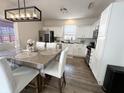 Bright kitchen with white cabinets, stainless appliances, wood floors, and modern lighting above the dining table at 8333 Sansa St, Indianapolis, IN 46113