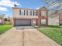 Charming two-story home featuring a brick and vinyl exterior, attached garage, and well-maintained front lawn at 8813 Browns Valley Ln, Indianapolis, IN 46113