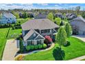 Aerial view of a beautiful suburban home featuring lush landscaping, a basketball court, and mature trees at 11509 Wildlife Ct, Zionsville, IN 46077