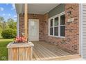 Close-up of a home's brick front porch with a wooden floor and a flower box at 13 N Main St, Brooklyn, IN 46111
