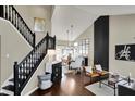 Open-concept living room with hardwood floors, black staircase and decorative lighting at 15890 Concert Way, Noblesville, IN 46060