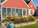 Red home with a screened-in porch and blooming flowers, creating an inviting curb appeal at 1646 Fisher Ave, Indianapolis, IN 46224