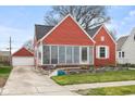Red home showcasing the exterior with a separate garage and well-maintained lawn and garden at 1646 Fisher Ave, Indianapolis, IN 46224