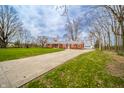 Inviting red brick home with a long driveway and detached garage nestled in a green yard at 1911 N Rangeline Rd, Anderson, IN 46012