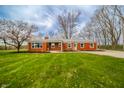 Well-maintained red brick home with a pristine lawn and picturesque landscaping at 1911 N Rangeline Rd, Anderson, IN 46012