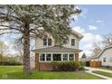 Charming two-story home with a brick foundation and a lovely front yard featuring a mature tree at 310 W 43Rd St, Indianapolis, IN 46208