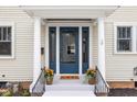 Welcoming entryway showcasing a stylish blue door flanked by potted plants and a 'HOME' welcome mat at 310 W 43Rd St, Indianapolis, IN 46208