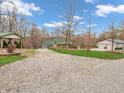View of a gravel driveway leading to a house and outbuildings surrounded by trees and grass at 3504 Morgan Oaks Cir, Martinsville, IN 46151