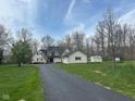 Traditional home showcasing a long driveway, lush lawn, and gray siding, complemented by dark shutters and a black roof at 4560 S 975 E, Zionsville, IN 46077