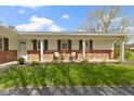 Inviting covered front porch with seating area, brick accents and green lawn at 5420 E 81St St, Indianapolis, IN 46250