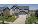 Charming gray two-story home showcasing a well-maintained lawn, professional landscaping, and a two-car garage at 6472 W Treeline Ln, McCordsville, IN 46055