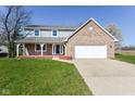 Charming two-story home features a brick facade, attached two-car garage, front porch, and a well-maintained lawn at 718 Marie Ln, Fortville, IN 46040