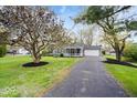 Single-story home featuring a cozy front porch and a paved driveway amidst a lush green lawn at 7709 Lewis Rd, Indianapolis, IN 46256