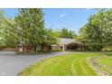 Traditional brick home boasts mature trees, green lawns, and a winding driveway at 8535 Washington Blvd, Indianapolis, IN 46240