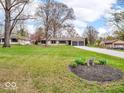 Lovely ranch-style home with a well-kept lawn, mature trees, and a long gravel driveway leading to a two-car garage at 8621 Manderley Dr, Indianapolis, IN 46240