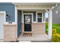 Close-up of the front door with black hardware, light brick accents, and a welcoming 'oh hello' doormat at 8694 Moyer Pl, Pendleton, IN 46064