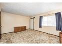 Spacious living room featuring neutral walls, patterned carpet, large window and storage cabinet for comfortable living at 9055 Panorama Ct, Indianapolis, IN 46234