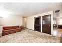 Comfortable living room featuring neutral walls, patterned carpet, brown sofa and dark stained doors at 9055 Panorama Ct, Indianapolis, IN 46234