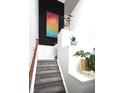 Carpeted stairway with white walls and trim, contrasted by black accent wall and colorful artwork at 967 Orlando St, Carmel, IN 46032