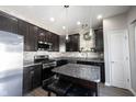 Modern kitchen with dark cabinets, granite countertops, stainless steel appliances, and a center island at 9770 Blue Violet Dr, Noblesville, IN 46060