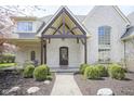 Charming covered front porch with brick and timber detailing and manicured landscaping at 10628 Walnut Creek W Dr, Carmel, IN 46032