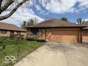 Brick exterior with lush green lawn, landscaping, paved driveway, and attached single car garage at 1215 Willow Springs Blvd, Brownsburg, IN 46112