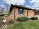 Brick exterior with blue shutters, a lawn, landscaping, and attached garage, offering classic curb appeal at 1215 Willow Springs Blvd, Brownsburg, IN 46112