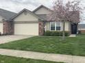 Charming single-story home featuring an attached garage, beautiful lawn, and blossoming tree at 1302 Lexington Trl, Greenfield, IN 46140