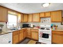 Cozy kitchen featuring wood cabinets, white appliances, and a window view at 13346 N Miller Dr, Camby, IN 46113